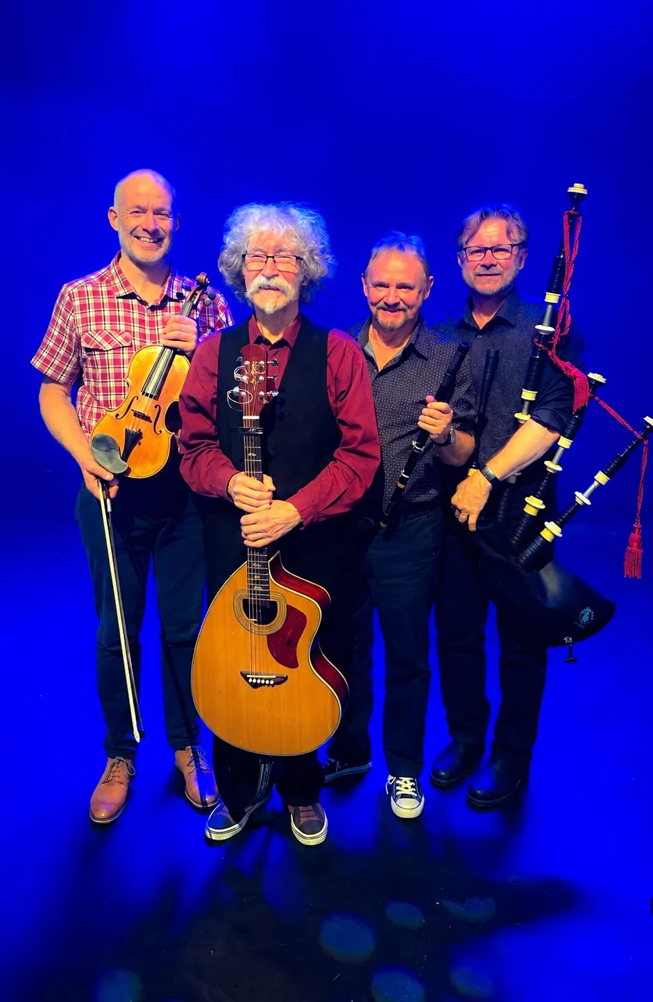 The four Tannahill Weavers holding a fiddle, guitar, flute, and bagpipes against a blue background.